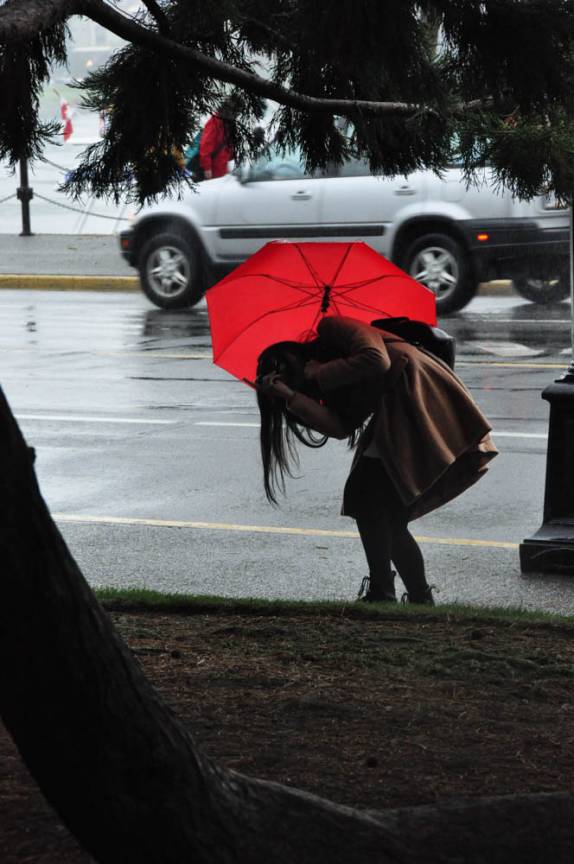 Em dia de chuva, turista se contorce para tirar sua fotografia em Victoria, capital da British Columbia, no oeste do Canadá